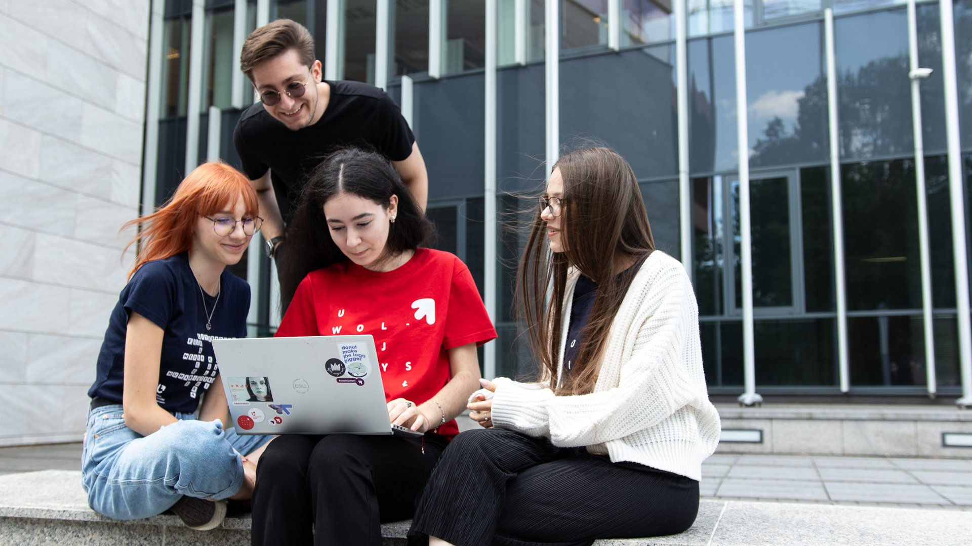 studenci z komputerem przed wydziałem