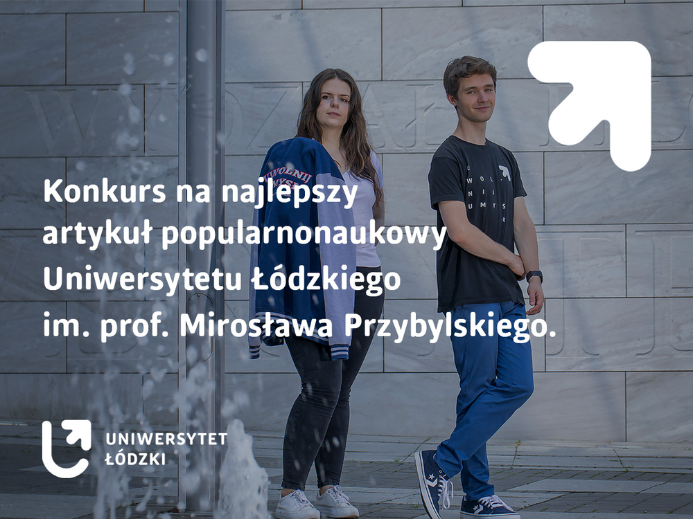 Studentka i student na tle szarej ściany z widocznymi wyrytymi literami. Na pierwszym planie tryskająca woda z fontanny.